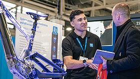 Two people are shaking hands at a trade show booth