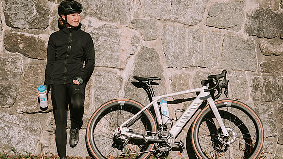 Muriel Mohr und ein Canyon E-Roadbike an eine Steinwand gelehnt 