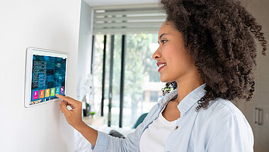 Frau tippt auf ein Smart Home Display