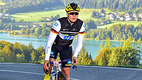 Profiradfahrer Alexander Steffens auf einem Rennrad im Hintergrund ein Bergsee