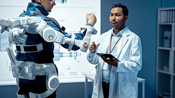 Two men test a robotic arm