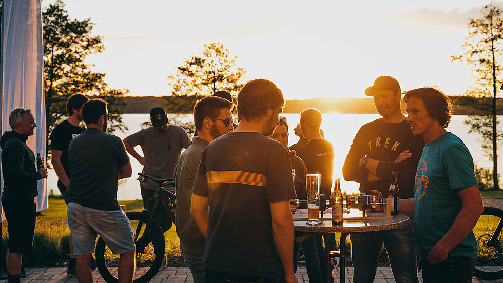 Gruppe von Mitarbeitern bei Sonnenuntergang am See 