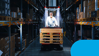 Man on a forklift truck in the warehouse between shelves
