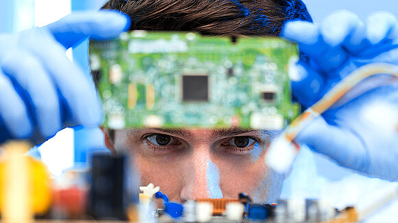 Man holds an embedded module in front of his face for testing