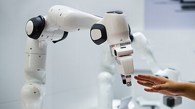 Eine Hand berührt einen Roboterarm