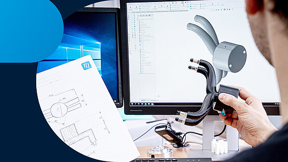 A person looks at a component and a drawing in front of a PC screen