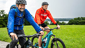 Oliver Zeidler und ein Mann nebeneinander auf E-Mountainbikes