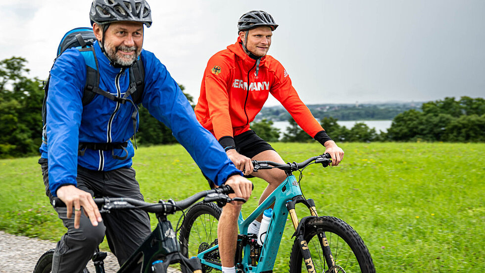 Oliver Zeidler und ein Mann nebeneinander auf E-Mountainbikes