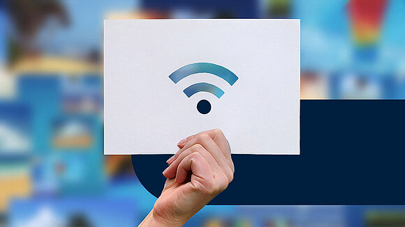 A hand is holding up a piece of paper with the Wi-Fi symbol on it