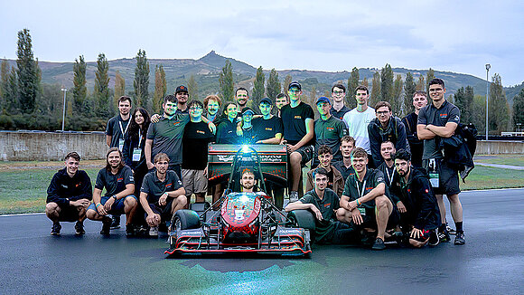 Group photo of the Starkstrom Augsburg Racing Team with a race car in the center