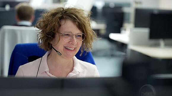 A TQ employee wearing a headset and looking at a computer screen