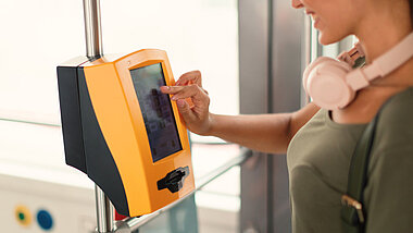 Eine Person tippt mit einem Finger auf das Display von einem Ticketautomat