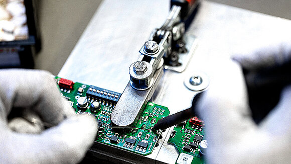 Detailed view of two gloved hands soldering a circuit board