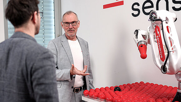Two men talking next to a medical cobot