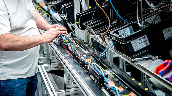 A person stands in front of a shelf with cables and components