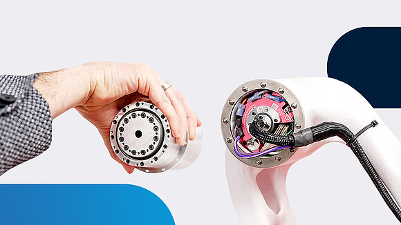 One hand holds a drive solution, and next to it is a motor integrated into a robotic joint with built-in electronics