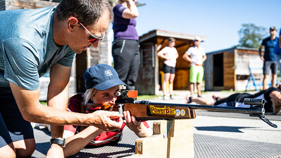 Ein Mann zeigt einer Frau das Schießen im liegen beim Biathlontraining
