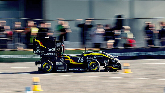 Picture of a black-and-yellow electric race car on the racetrack