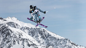Freeskierin Muriel Mohr beim Springen im Hintergrund die schneebedeckten Berge