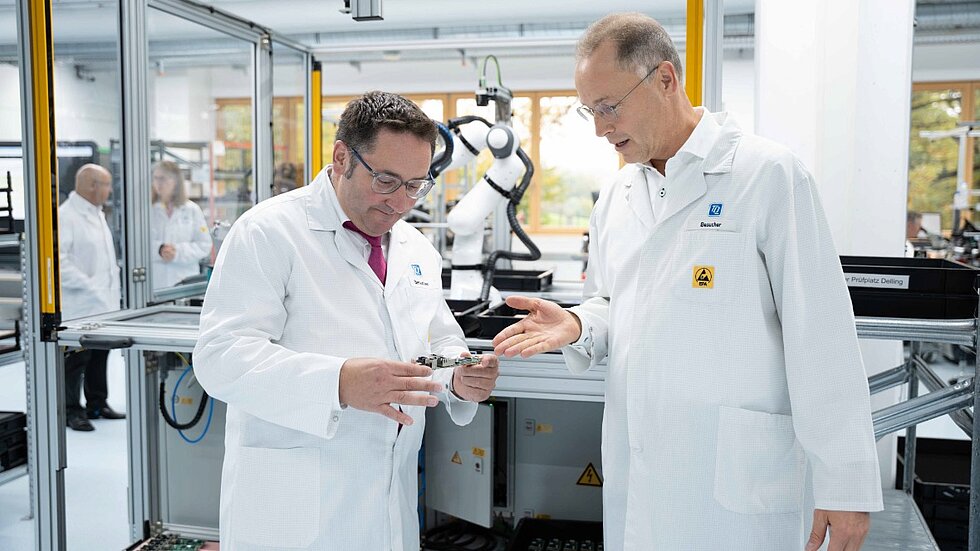 Rüdiger Stahl from TQ shows Tobias Gotthardt an electronic component on the production line