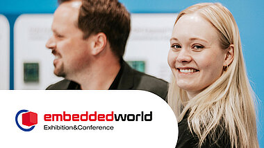2 Personen von TQ mit einem Banner von der embedded world