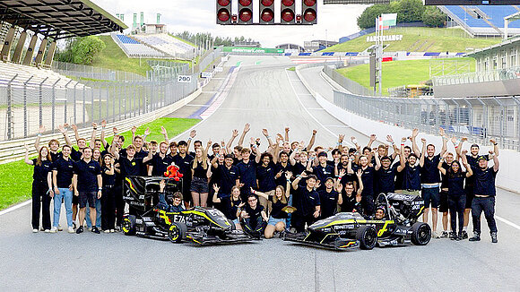 Group photo of the KA Racing Team at a racetrack