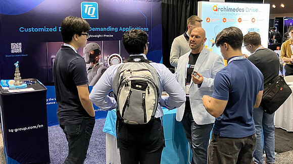 A TQ-RoboDrive employee at the booth talking with visitors