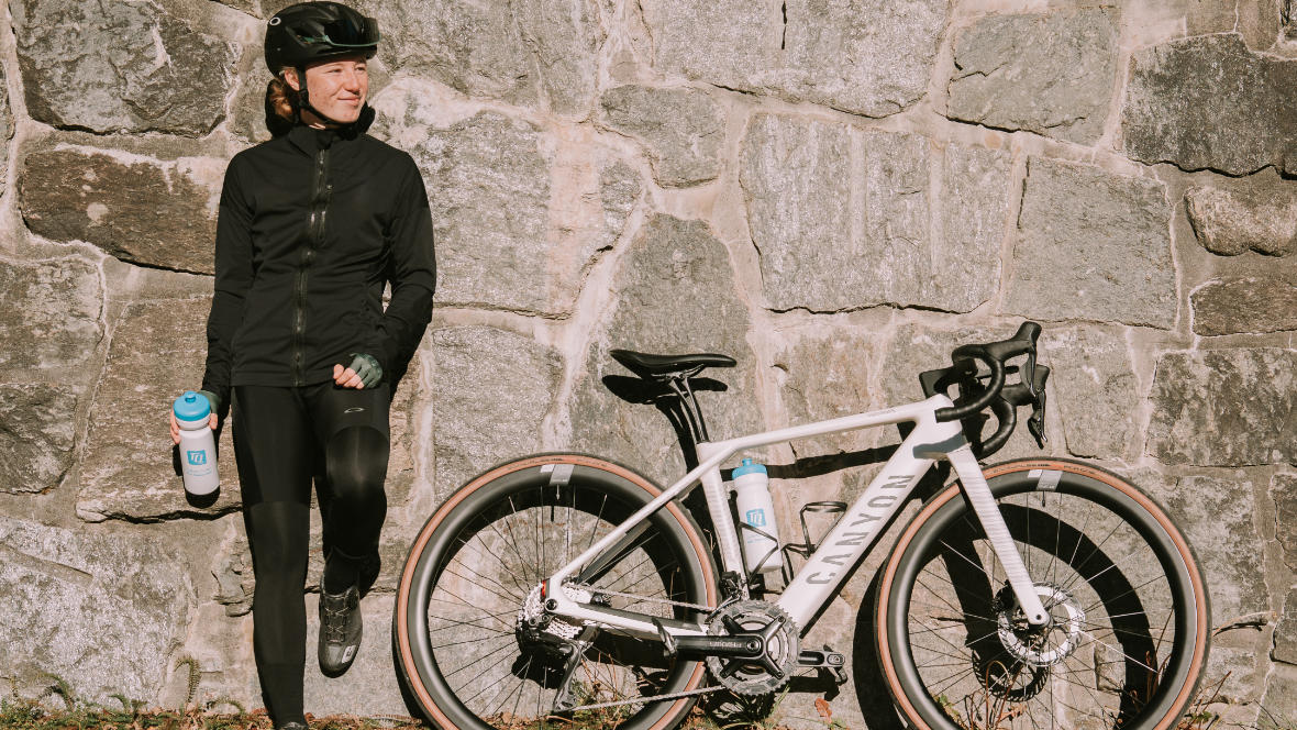 Muriel Mohr und ein Canyon E-Roadbike an eine Steinwand gelehnt 
