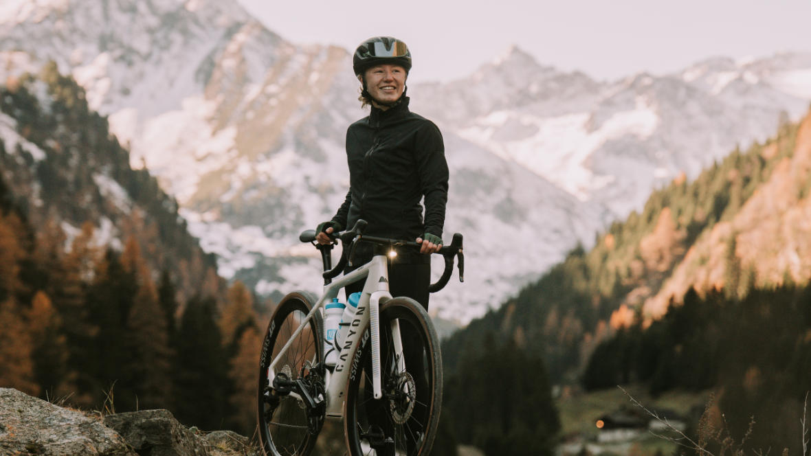 Athletin Muriel Mohr mit einem Canyon E-Roadbike im Hintergrund Berge