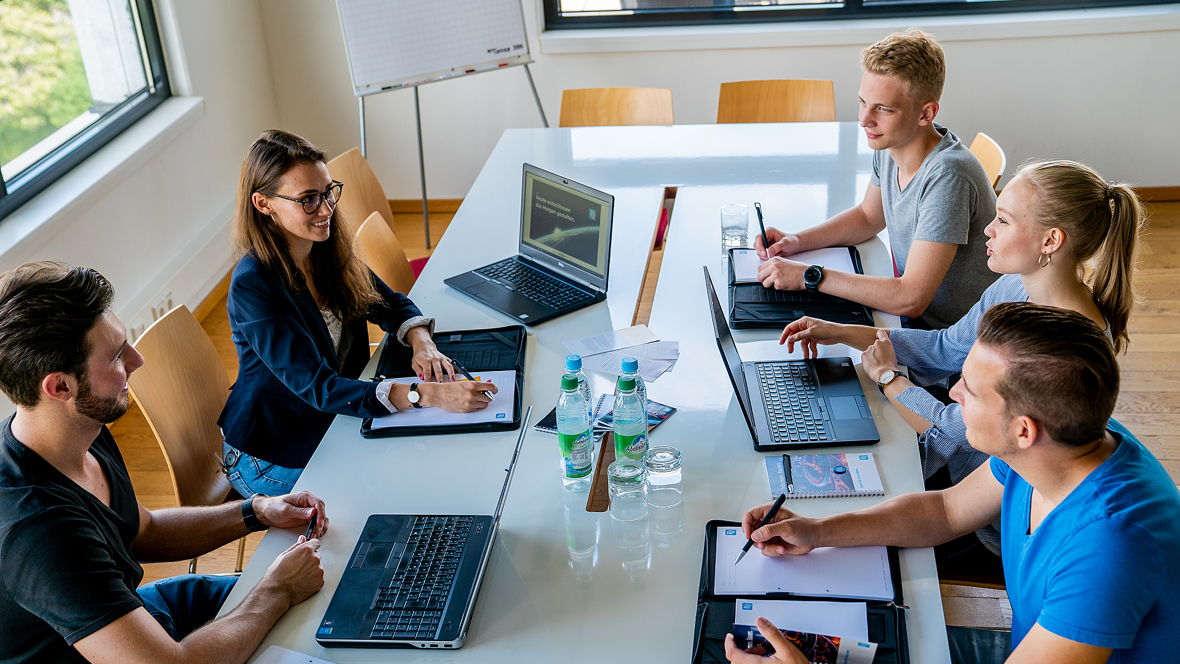 Personengruppe an einem Konferenztisch mit Laptops