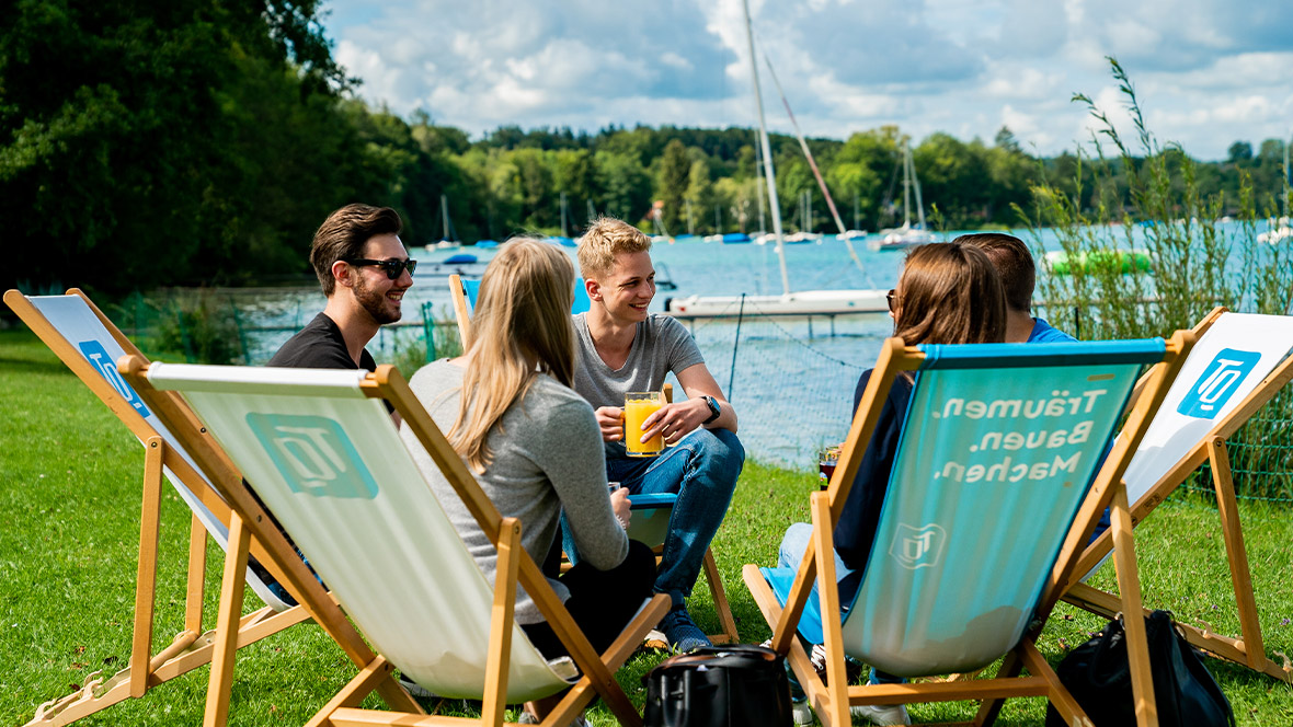 Gruppe von technischen Auszubildenden sitzen am See 