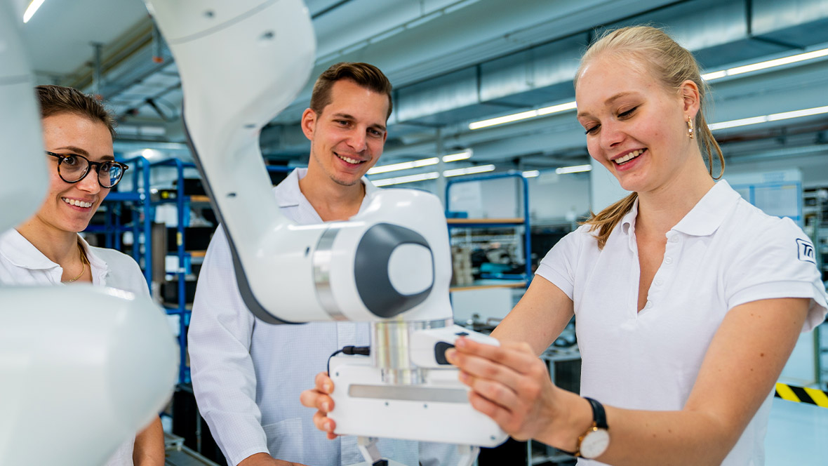 Technische Auszubildende bedient Cobot