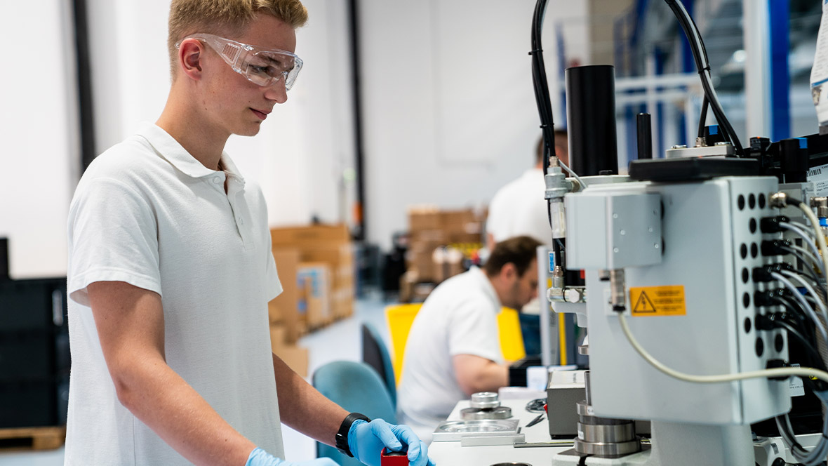 Technischer Auszubildender bedient Maschine
