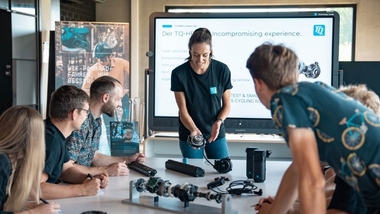 Eine Frau präsentiert einer Gruppe an Personen das TQ HPR E-Bike System