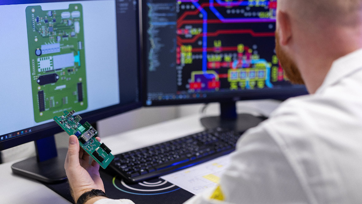 Mann mit Embedded Modul vor einem PC