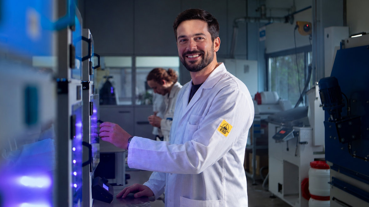A man in an ESD coat stands in front of 3D printers