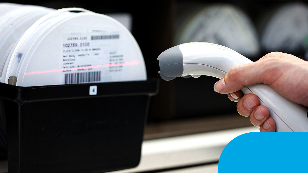 Eine Hand mit einem Scanner scannt eine Box mit einem Barcode