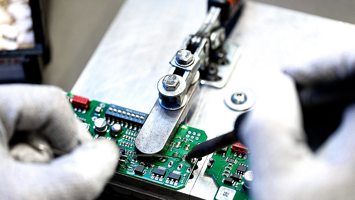 Detailed view of two gloved hands soldering a circuit board