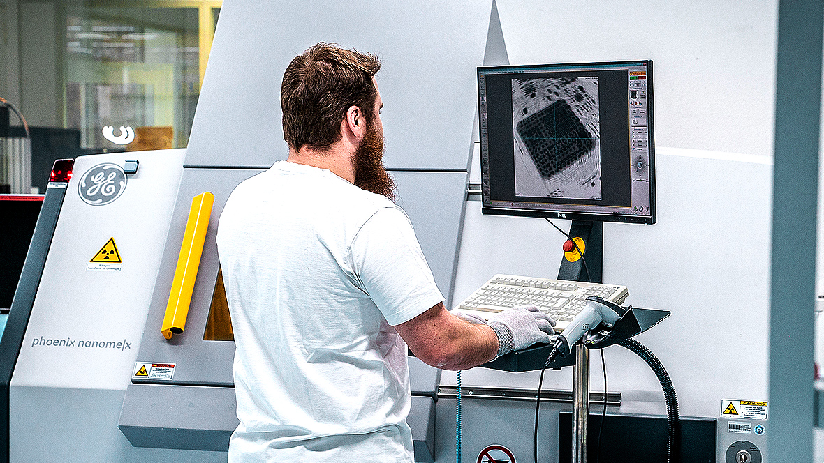 A man diagonally from behind at an X-ray analyzer