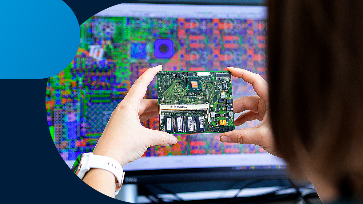 A person holds an embedded module in front of a PC screen