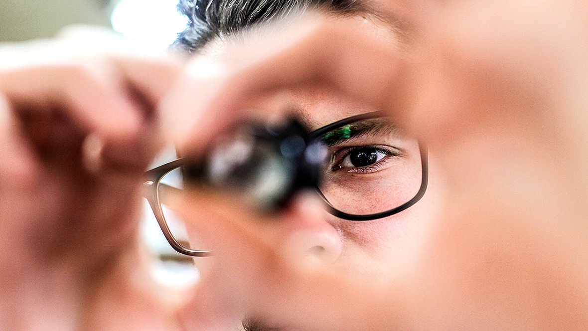 Person mit Brille schaut durch eine Linse
