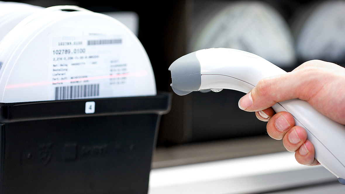 One hand holds a scanner and scans a barcode
