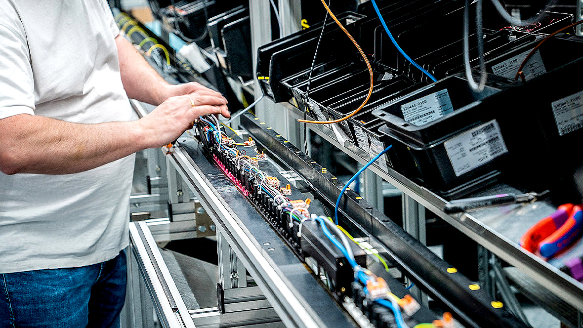 A person stands in front of a shelf with cables and components