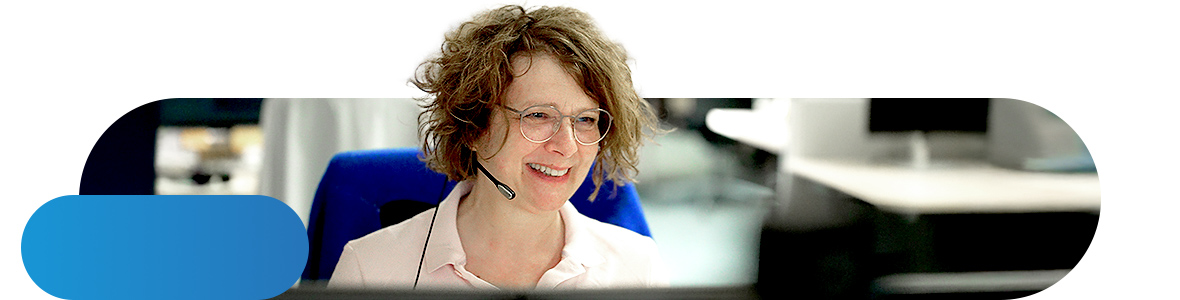 A woman wearing a headset is sitting in front of a screen