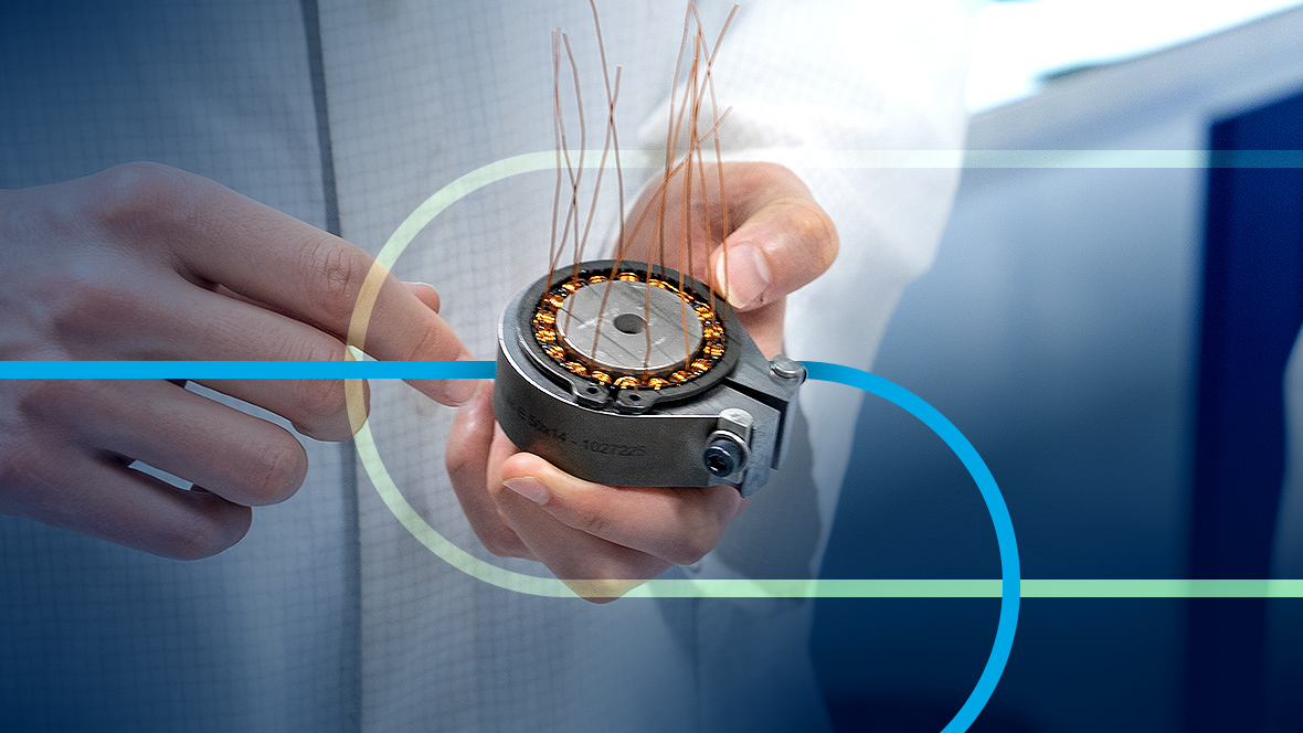 A hand is holding a torque motor with visible copper wires