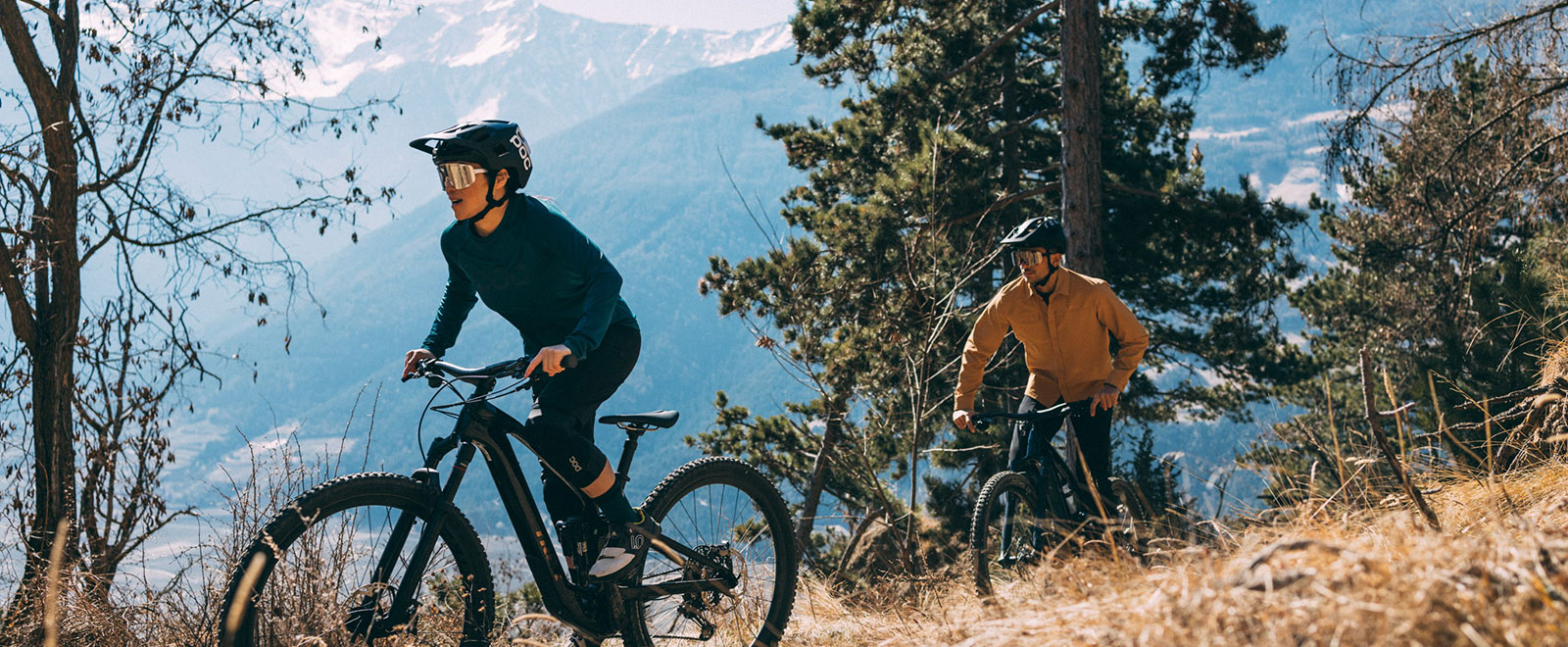 E-bike rider with Trek Fuel EXe in front of sunny alpine scenery